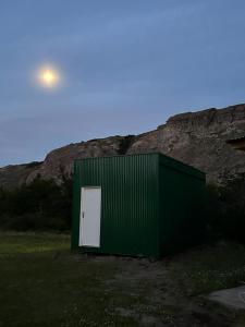 ein grünes Gebäude mit einer weißen Tür vor einem Berg in der Unterkunft Fitz Roy Hostería de Montaña - El Chaltén in El Chalten