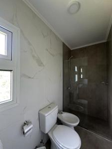 a white bathroom with a toilet and a shower at Fitz Roy Hostería de Montaña - El Chaltén in El Chalten