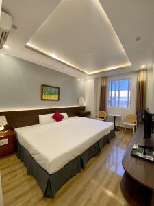 een slaapkamer met een groot wit bed en een bureau bij Dolphin Hotel in Cat Ba