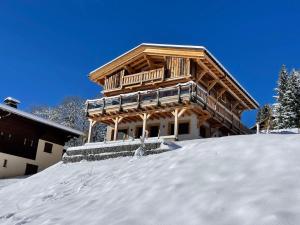ein großes Holzhaus auf einem schneebedeckten Hang in der Unterkunft Chalet de standing avec jacuzzi et ski-room, 5 chambres - FR-1-505-199 in Notre-Dame-de-Bellecombe