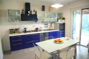 Domus Aurige في مسينة: مطبخ مع دواليب زرقاء وطاولة مع صحن من الفاكهة