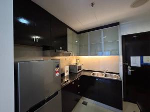 een keuken met zwarte kasten en een roestvrijstalen koelkast bij New-SunwayLagoonFamilySuite-highest floor-2-4pax-Netflix-Balcony-SuperFastInternet in Petaling Jaya