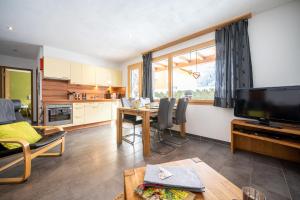 a kitchen and living room with a table and a television at Chasa Sotchà Dadora 698 in Scuol