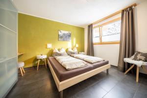 um quarto com uma cama e uma parede amarela em Chasa Sotchà Dadora 698 em Scuol