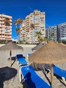 a group of straw umbrellas and chairs on a beach at Horizonte Azul in Calpe