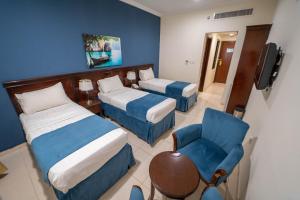 une chambre d'hôtel avec deux lits et une chaise dans l'établissement فندق نما مودة Namma Mawaddah Hotel, à La Mecque 11 autres photos