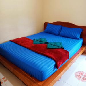 a bed with blue sheets and green bows on it at Lanta Orange House in Ko Lanta