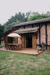 a house with a deck with a table and an umbrella at Maison Typique Landaise in Moliets-et-Maa