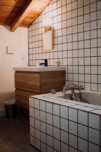 a white tiled bathroom with a sink and a tub at Maison Typique Landaise in Moliets-et-Maa