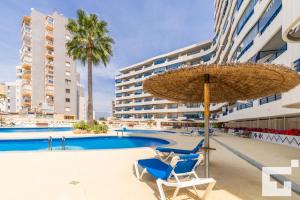 una piscina con due sedie e un ombrellone di Apartamento Turquesa Beach 36D - Grupo Turis a Calpe