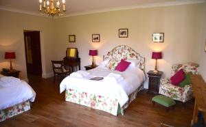 a bedroom with two beds and two chairs at Delphi Lodge in Leenaun