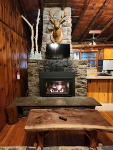 una chimenea de piedra en una sala de estar con mesa en Adirondack Diamond Point Lodge, en Lake George