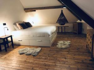 una camera con letto bianco e pavimento in legno di L’idée du jour a Onhaye