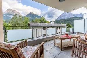 a balcony with a table and chairs and mountains at La Stüvetta in Scuol