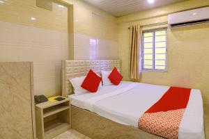 een slaapkamer met een bed met rode kussens en een raam bij Hotel Royal Inn in Calcutta