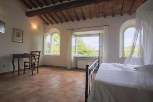 a bedroom with a bed and a table and windows at Hotel Santo Stefano in Portoferraio