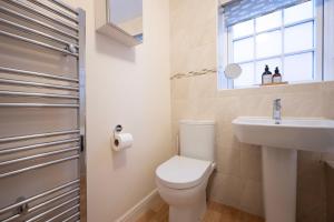 a bathroom with a toilet and a sink and a window at The Marlowe - Beautiful house in the heart of Canterbury with Free Parking in Canterbury