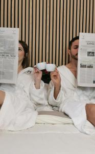 un hombre y una mujer acostados en la cama con toallas sosteniendo tazas en B&B Il Vico del Greco, en Le Castella