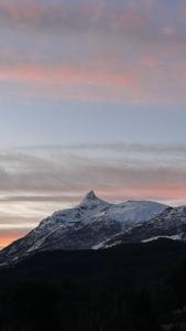 a mountain with snow on it in front of a sunset at refugio lonconao in Futaleufú