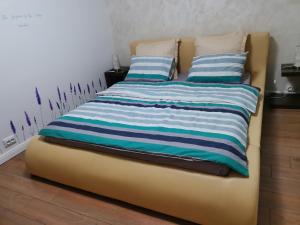 a yellow bed with blue and white striped sheets and pillows at ARKA Apartment in Craiova