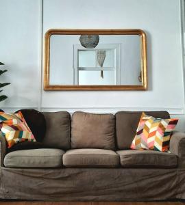 a brown couch in a living room with a mirror at Casa Malva - Traditional townhouse apartment in Monchique