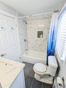 a white bathroom with a toilet and a bath tub at Elegant 1 Bed Montrose - Rome @The Italian Plaza in Houston +15 photos