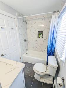 a white bathroom with a toilet and a bath tub at Elegant 1 Bed Montrose - Rome @The Italian Plaza in Houston