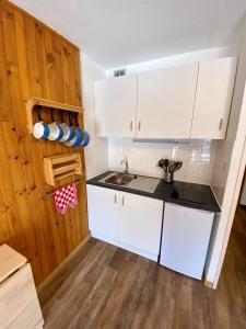 una pequeña cocina con armarios blancos y fregadero en Centre station - LA FOUX D'ALLOS - Charmant T2 en Allos