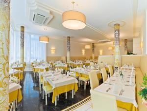 a restaurant with white tables and yellow chairs at Hotel Montecarlo in Bibione