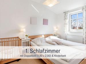 ein weißes Schlafzimmer mit einem Bett und einem Fenster in der Unterkunft Bio Ferienhof Wichtelweide - Fewo Thymian in Fehmarn + 46 Fotos