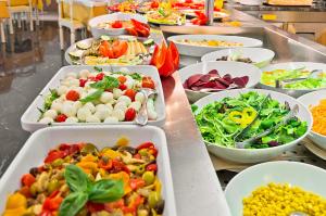 a buffet line with many trays of different types of food at Hotel Montecarlo in Bibione