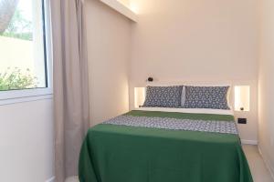 una camera con letto verde e finestra di Villa Muscì a Tortolì