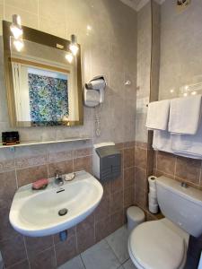 ein Badezimmer mit einem Waschbecken, einem WC und einem Spiegel in der Unterkunft Hotel Le Ponteil in Antibes