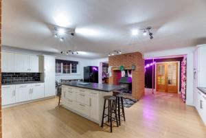 a kitchen with white cabinets and a brick wall at Hen & Stag Retreat Weekend Stay Sleeps 10 to 30 in Thetford