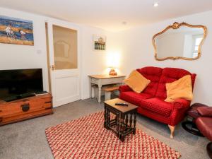 a living room with a red couch and a television at Sea Spray in Eyemouth