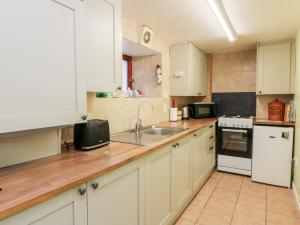 艾茅斯的住宿－Sea Spray，厨房配有白色橱柜和水槽