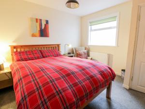 a bedroom with a red plaid bed and a chair at Sea Spray in Eyemouth