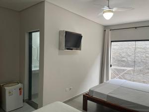 1 dormitorio con 1 cama y TV en la pared en Pousada Favo de Mel - Unidade 2 en Guarujá
