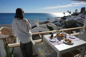 a woman standing on a balcony looking at the ocean at La Casa de Colores in Estepona