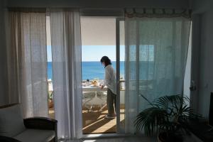 kobieta stojąca na balkonie z widokiem na ocean w obiekcie La Casa de Colores w mieście Estepona