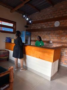 a woman standing at a counter in a restaurant at Iziba lodge in Hoima