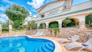 eine Villa mit einem Pool und einem Haus in der Unterkunft Costacabana - Villa Cleo in Lloret de Mar