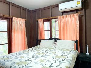 a bedroom with a bed and two windows at Koh Yao Noi Garden Home in Ban Nai Khlong