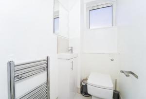 a white bathroom with a toilet and a window at Spacious modern family bedroom in Central London in London