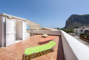 a balcony with green chairs and tables on a house at I Tre Golfi - Appartamenti con Terrazzo in San Vito lo Capo