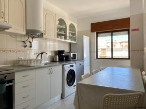a kitchen with a table and a washing machine at Blife Julya private rooms in Faro +18 photos