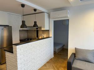Project Comfort Apartament Grzybowska 30/1211 في وارسو: مطبخ وغرفة معيشة مع منضدة من الطوب