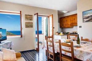 a kitchen and dining room with a table and a view of the ocean at GOCCE VILLAS - Casa Maradona in Nerano