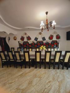 a dining room with a long table and chairs at Sub Creasta Cocosului in Breb