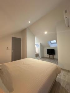 a white bedroom with a bed and a television at La Dépendance in Losne